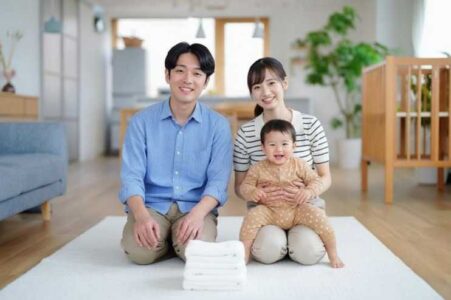 明るい室内で家族3人が笑顔で座っている写真